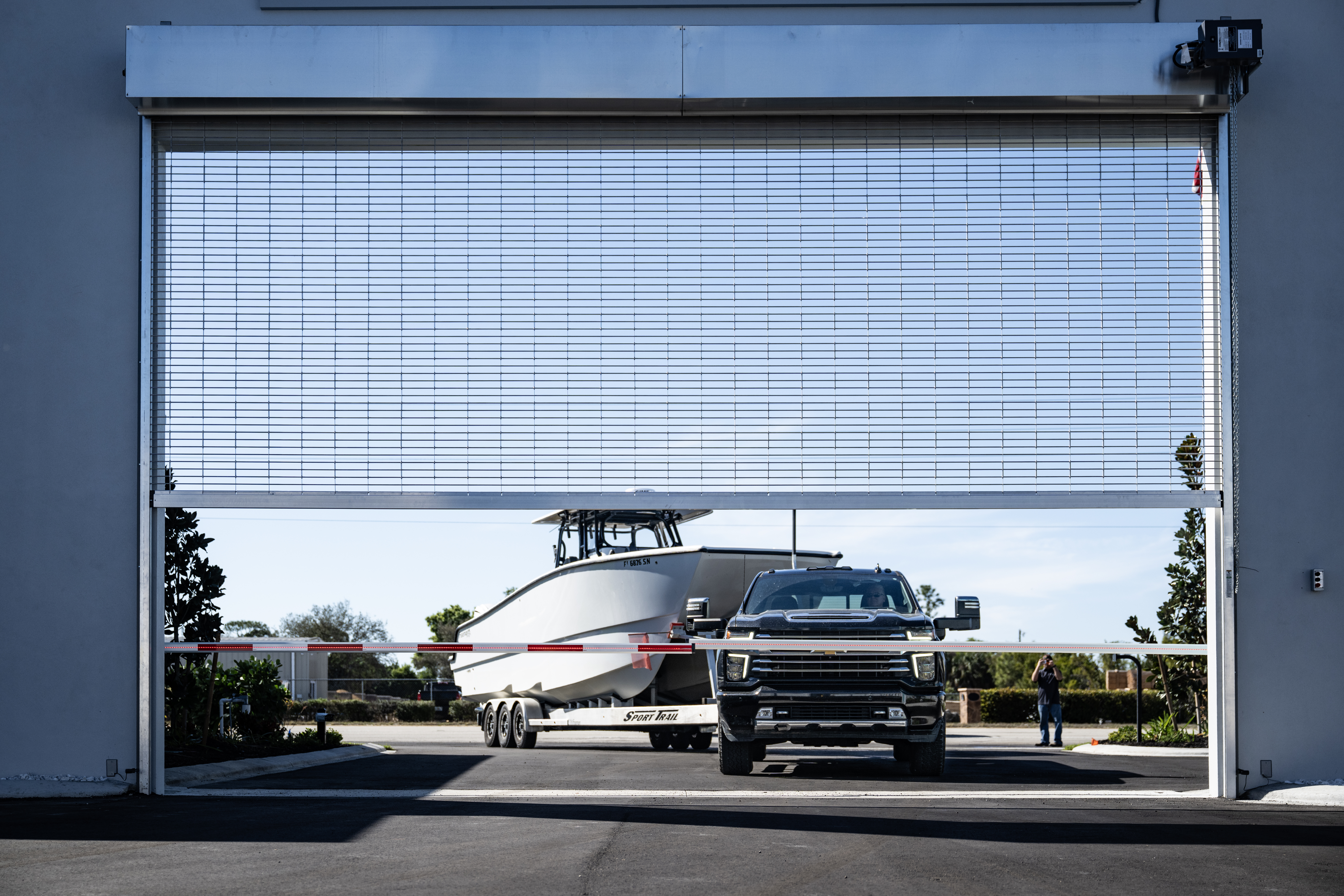 Main entry gate at MetroMaxx RV & Boat Storage showing a truck towing a large boat entering the secure gated facility in Fort Myers, Florida